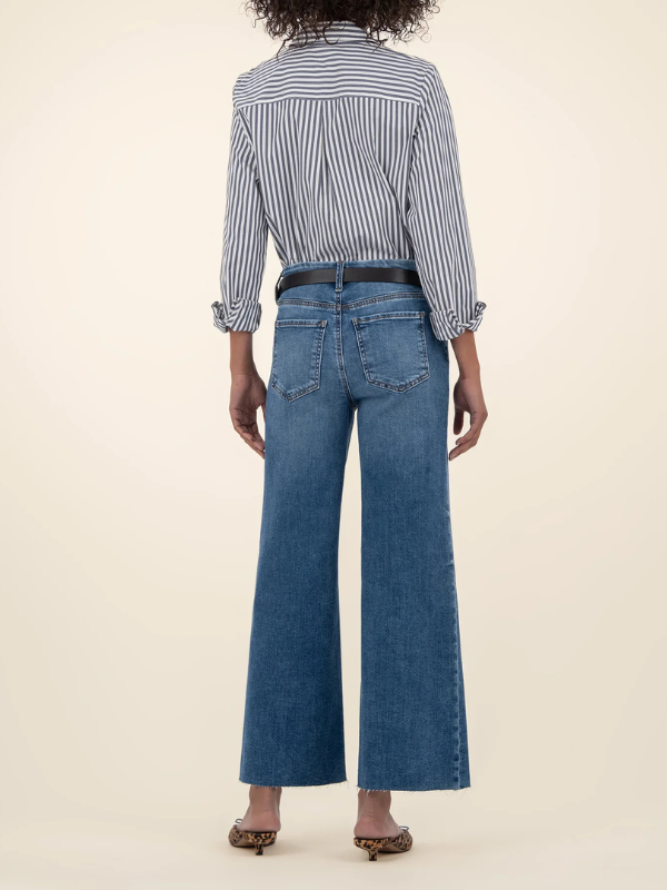 Person wearing a striped shirt and blue jeans on a beige background