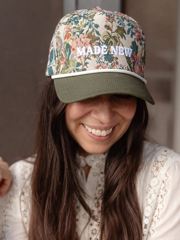 Person wearing a floral-patterned cap with 'MADE NEW' text, smiling.
