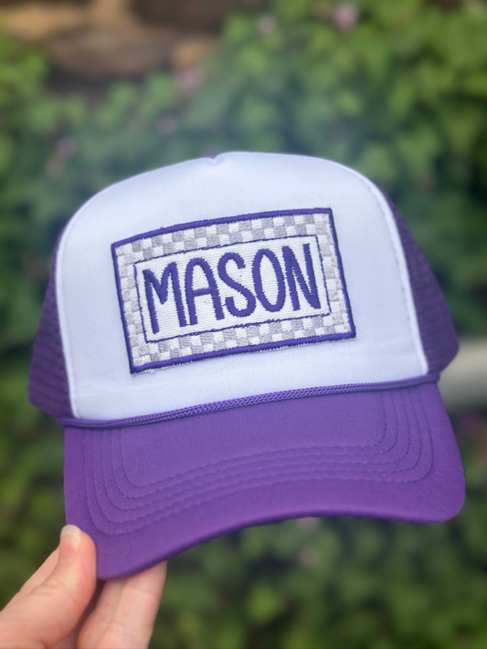 Purple and white cap with 'MASON' text on a blurred green background