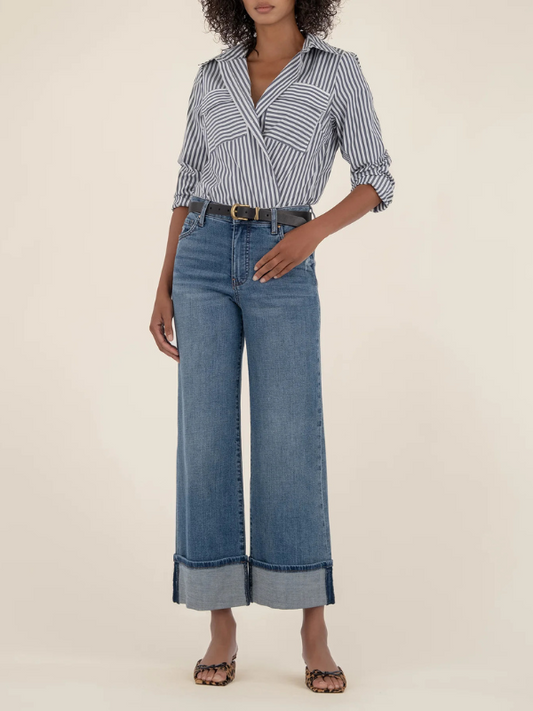 Woman wearing a striped shirt and wide-leg jeans on a beige background