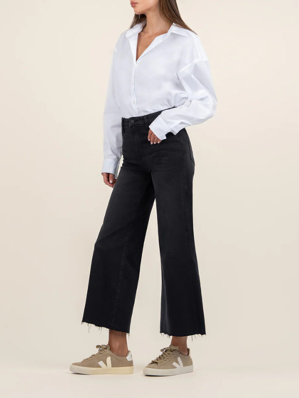 Person wearing a white shirt and black pants on a beige background
