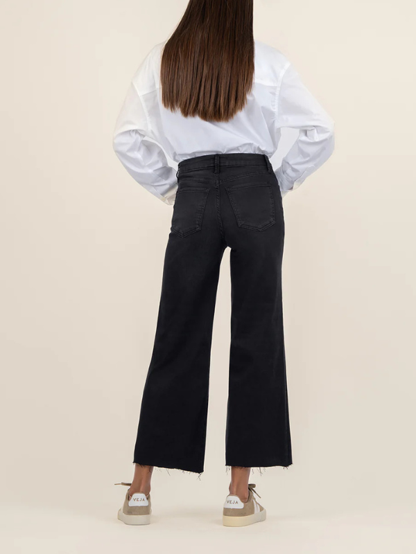 Person wearing a white blouse and black pants on a beige background