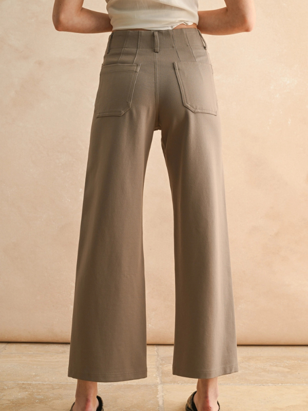 Person wearing beige wide-leg pants against a beige background
