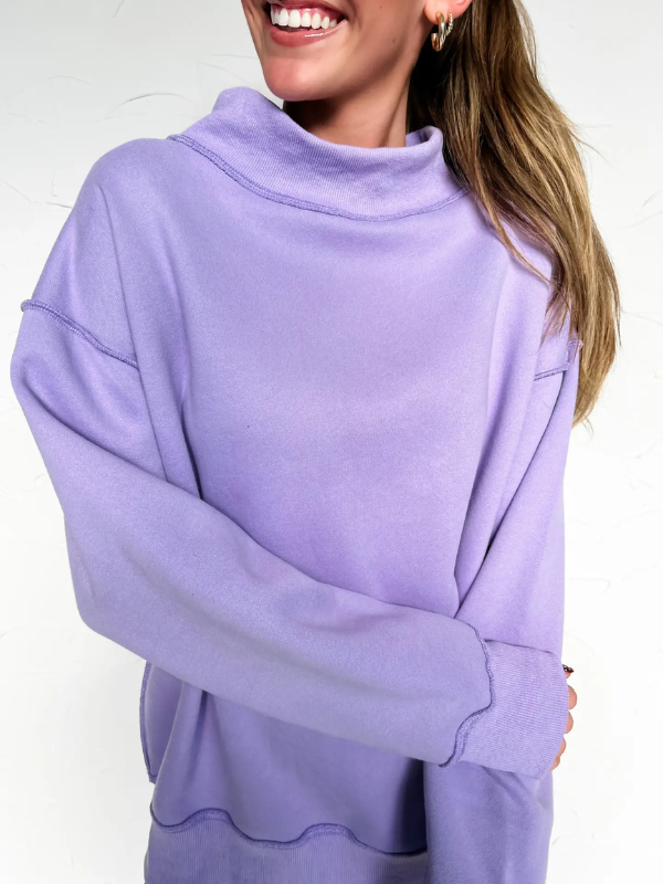 Person wearing a light purple sweater with a plain background