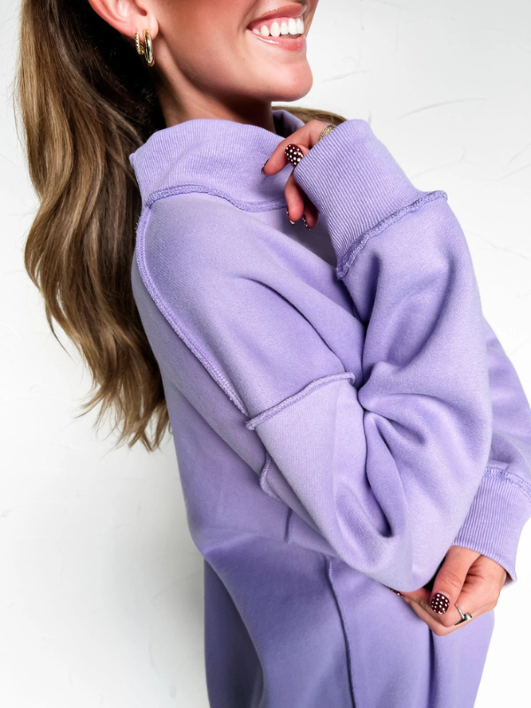 Person wearing a light purple hoodie with a plain background