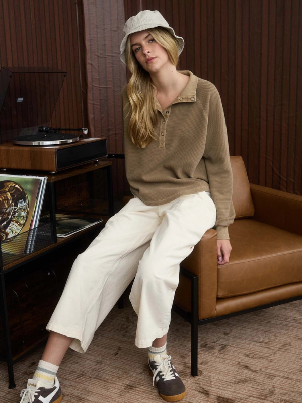 Woman sitting on a brown leather couch in a room with a record player and vinyl records.