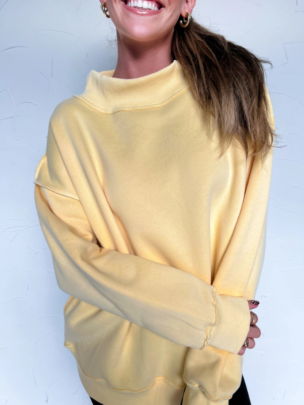 Person wearing a yellow sweatshirt against a light blue background