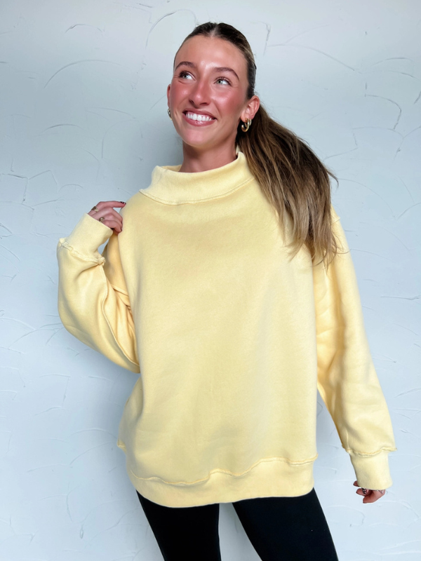 Person wearing a yellow sweatshirt against a light gray background
