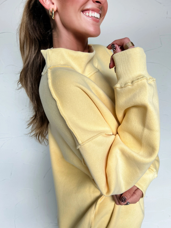 Person wearing a yellow oversized hoodie against a plain background
