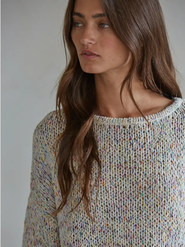 Woman wearing a multicolored knit sweater against a neutral background