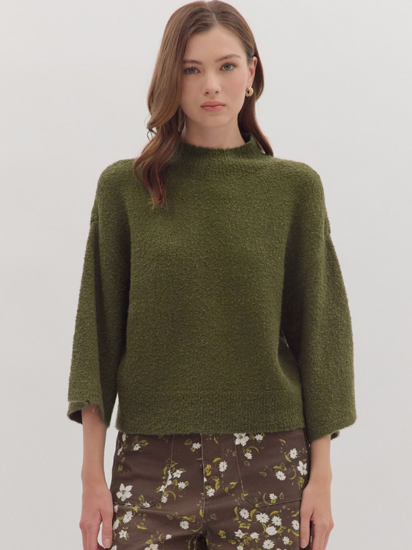 Woman wearing a green sweater with floral pants on a white background