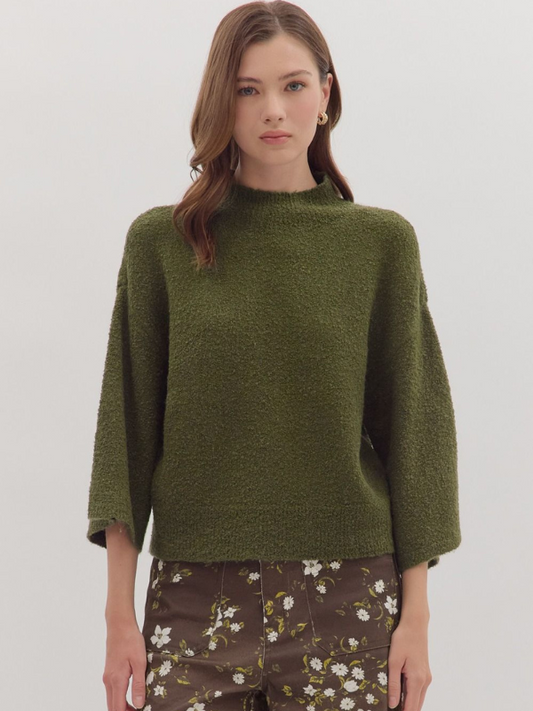 Woman wearing a green sweater with floral pants on a white background