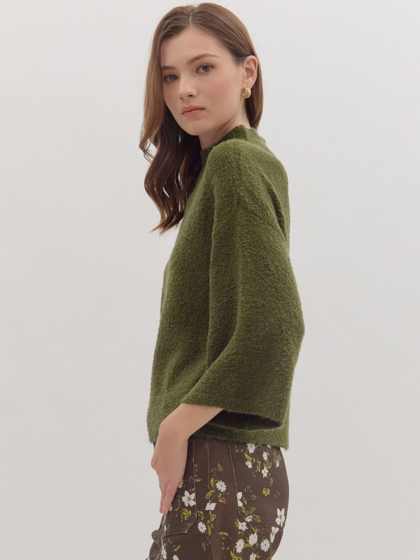 Woman wearing a green sweater with a plain background