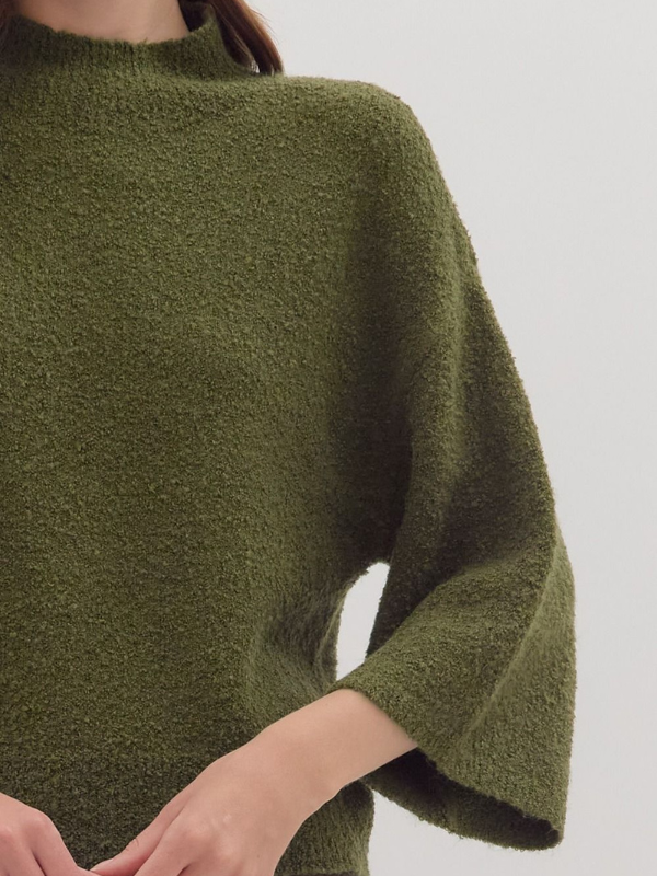 Green poncho worn by a person on a plain background
