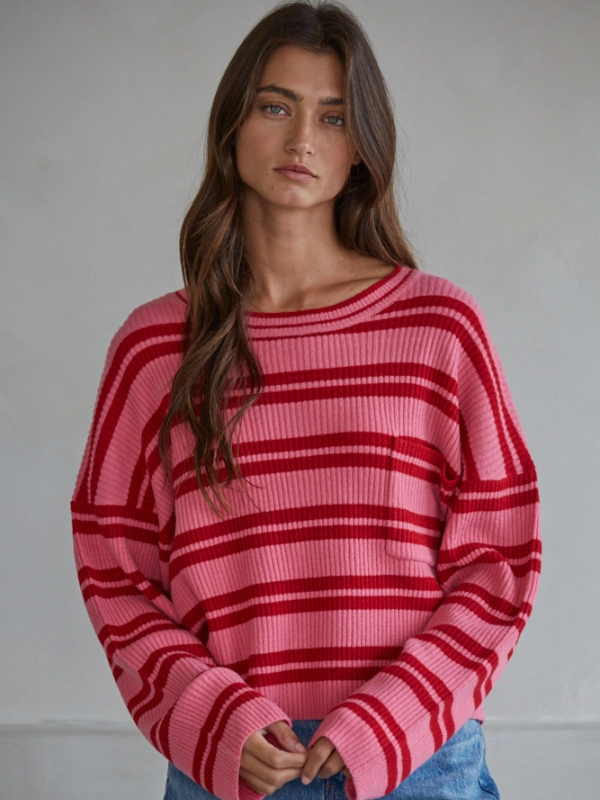 Woman wearing a pink and red striped sweater against a plain background