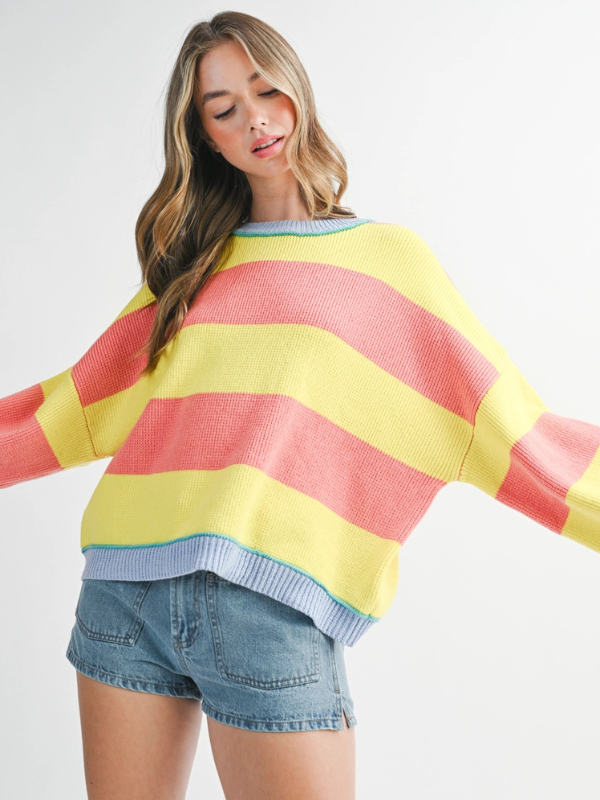 Woman wearing a colorful striped sweater and denim shorts on a white background