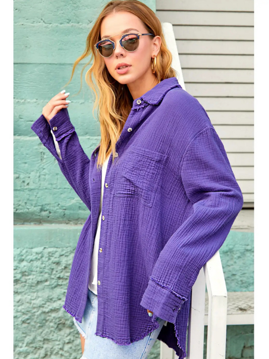 Woman wearing a purple shirt and sunglasses against a green wall.