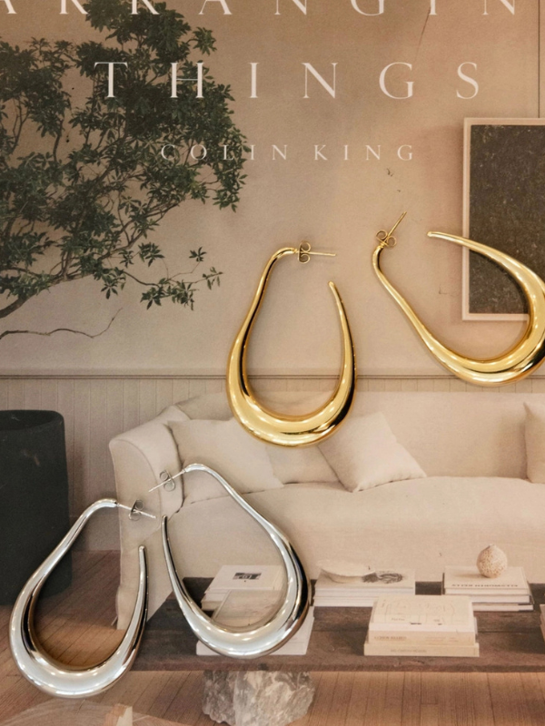 Gold and silver earrings displayed on a sofa with decorative elements.