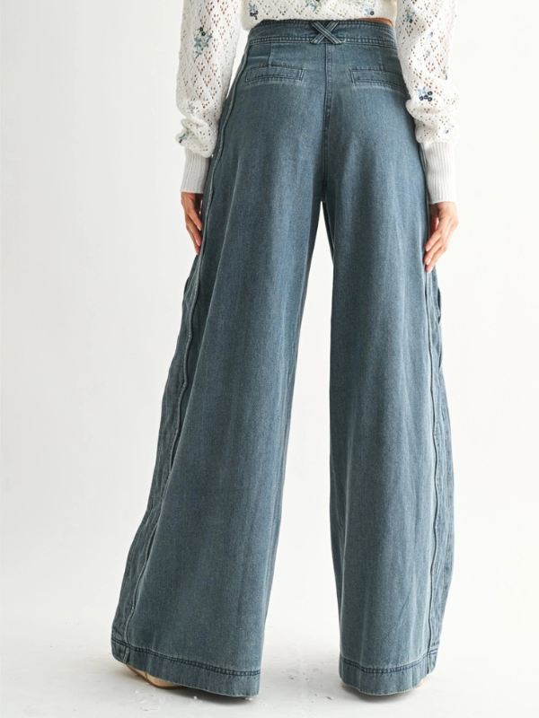 Blue wide-leg jeans worn by a person on a white background