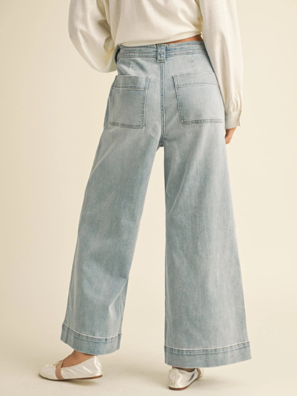 Light blue wide-leg jeans worn by a person on a beige background