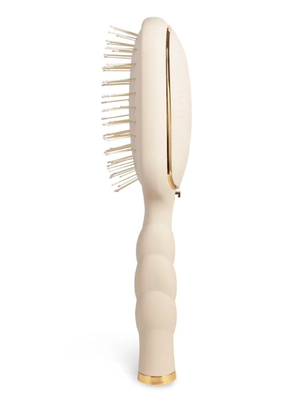 Beige hairbrush with gold accents on a white background