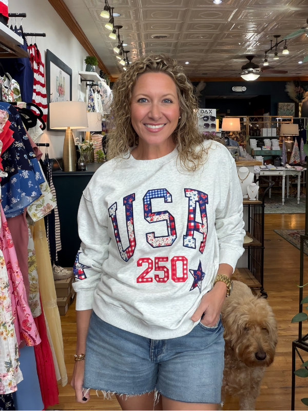 Woman wearing a 'USA 250' sweatshirt in a store with a dog.