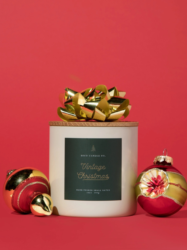 Candle with a gold bow and Christmas ornaments on a red background