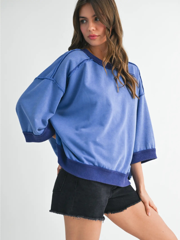Woman wearing a blue oversized sweatshirt and black shorts on a white background