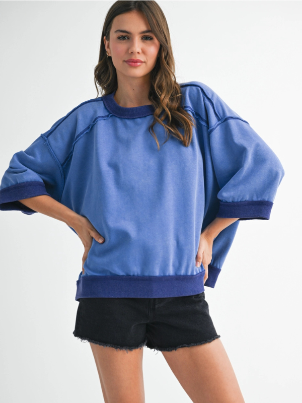 Woman wearing a blue oversized sweater and black shorts on a white background