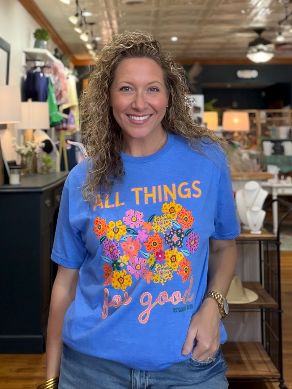 Woman wearing a blue t-shirt with colorful floral design and text in a store setting