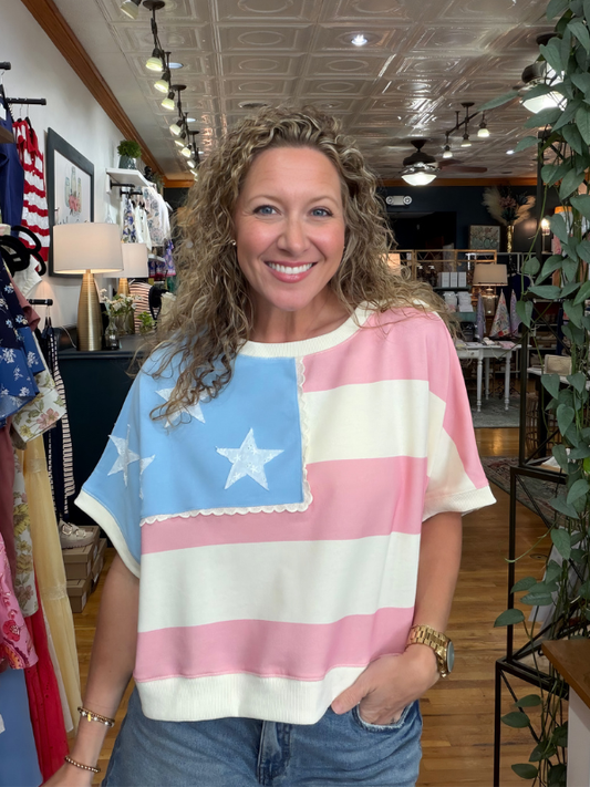 Woman wearing a colorful flag-themed shirt in a store setting