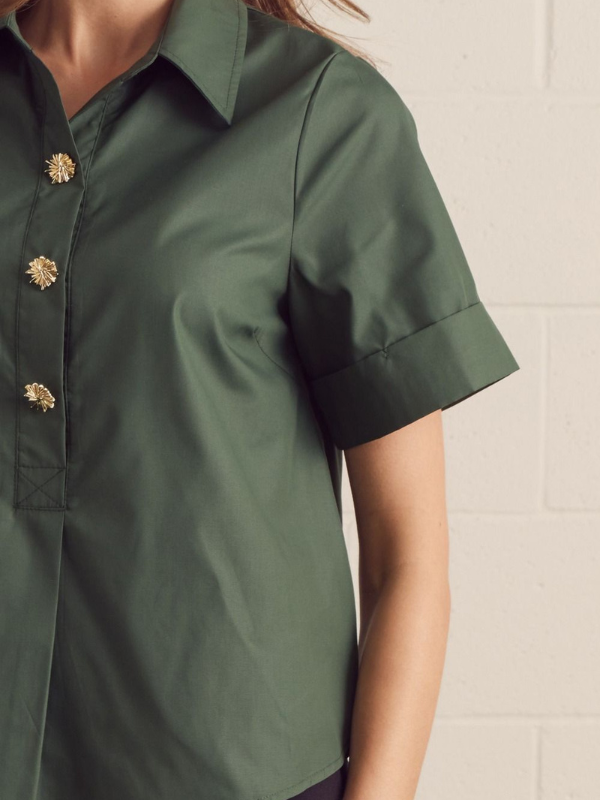 Green shirt with gold buttons on a neutral background