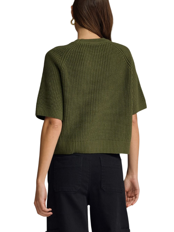 A woman shown from the back wearing a short-sleeve ribbed knit sweater in olive green and black pants, against a plain white background.