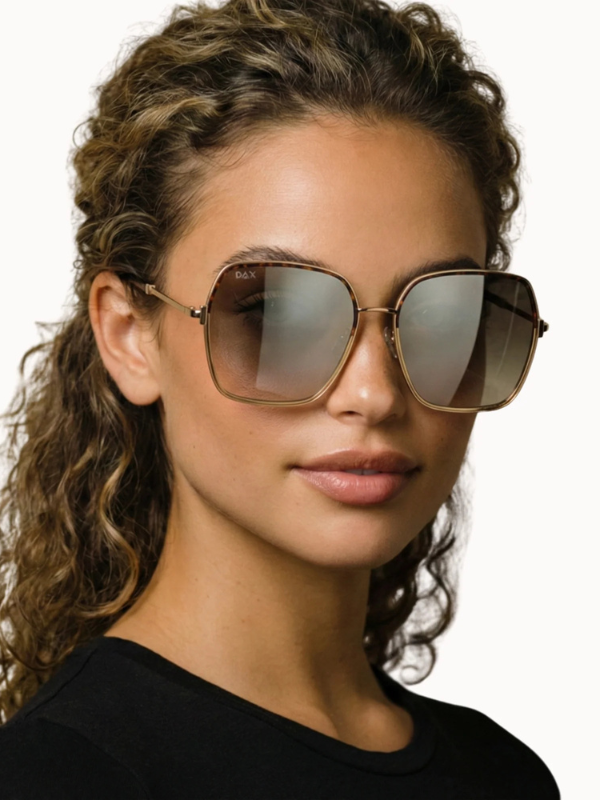 Woman wearing gold-framed sunglasses with a neutral background