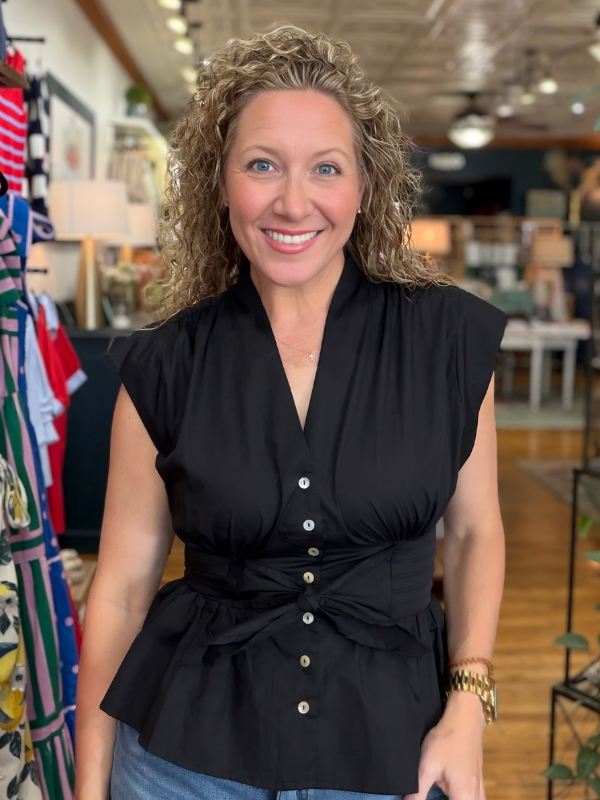 Woman wearing a black sleeveless top with buttons in a store setting