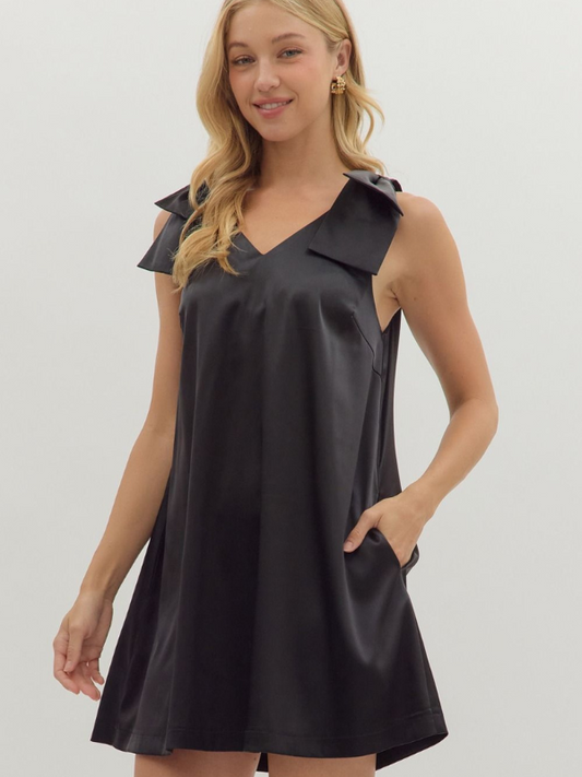 Woman wearing a black sleeveless dress with a collar on a light gray background