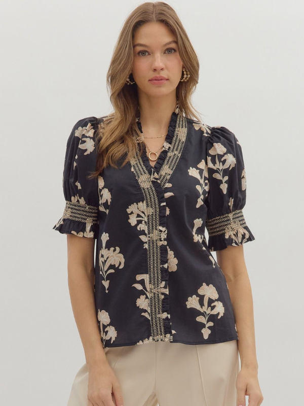 Woman wearing a navy blue blouse with floral patterns on a white background