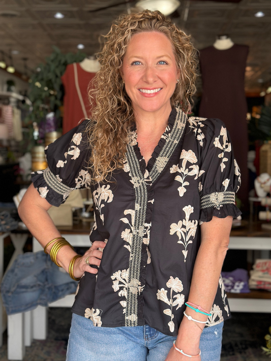 Woman wearing a black floral blouse in a store setting