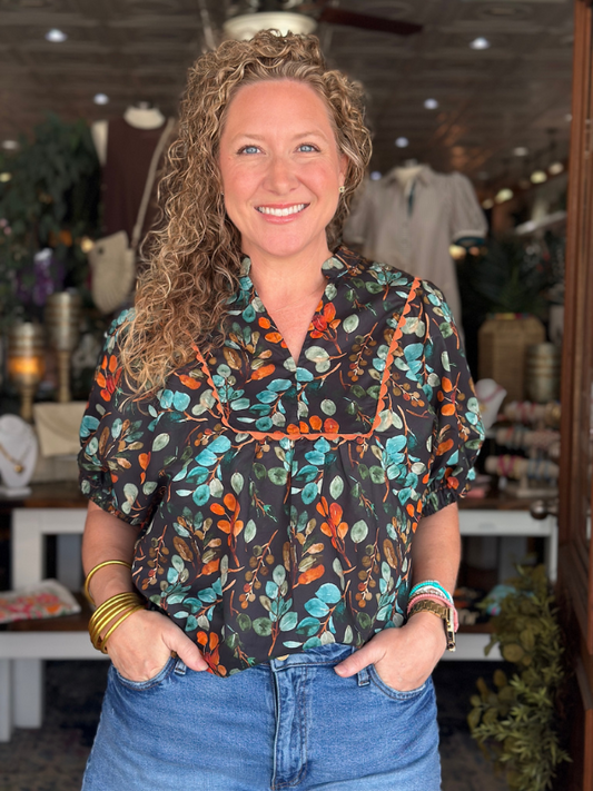 Woman wearing a colorful floral blouse in a store setting