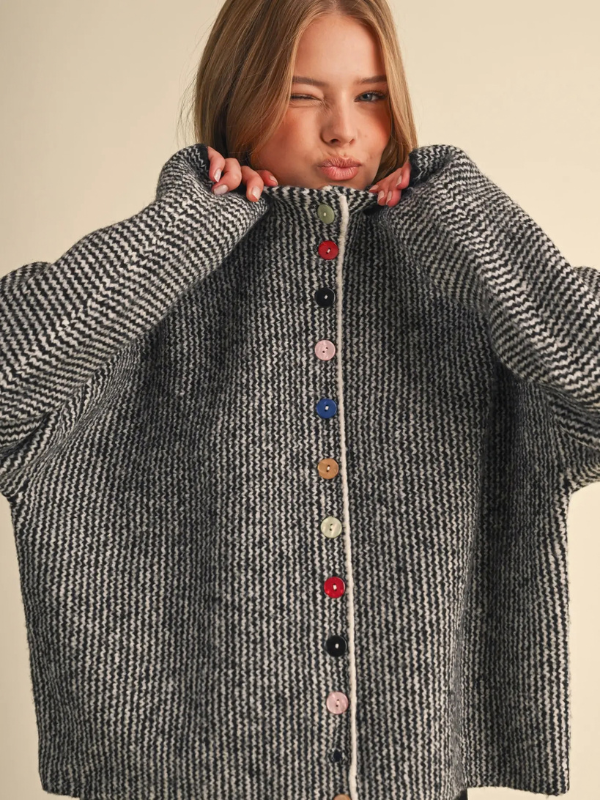 woman wearing a black and ivory sweater with colorful buttons 