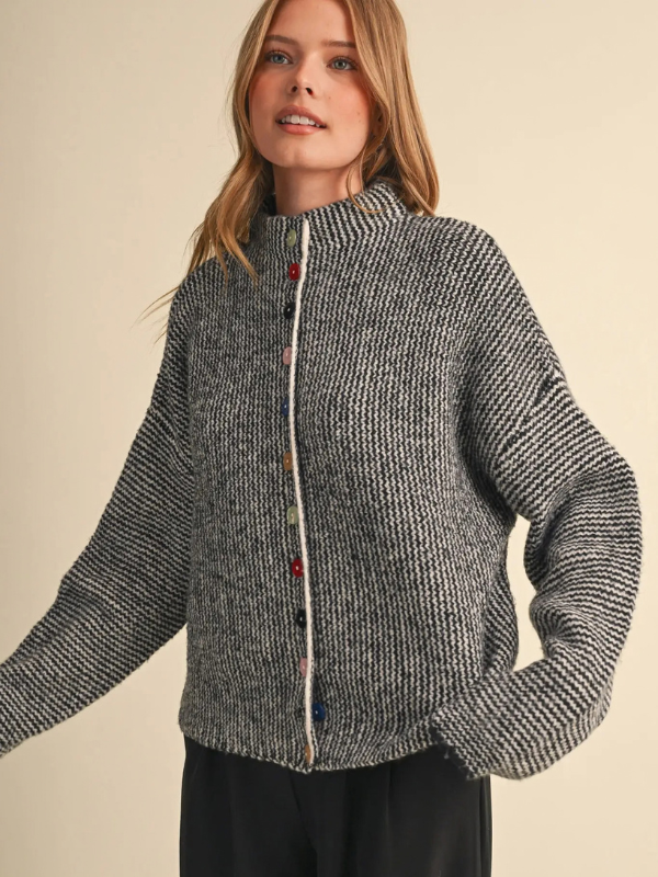 woman wearing a black and ivory sweater with colorful buttons 