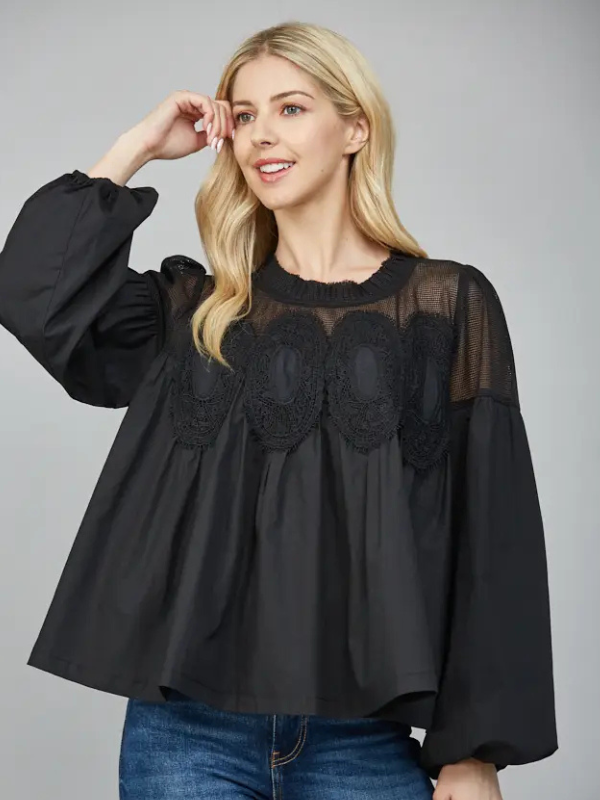 Woman wearing a black blouse with lace details on a gray background