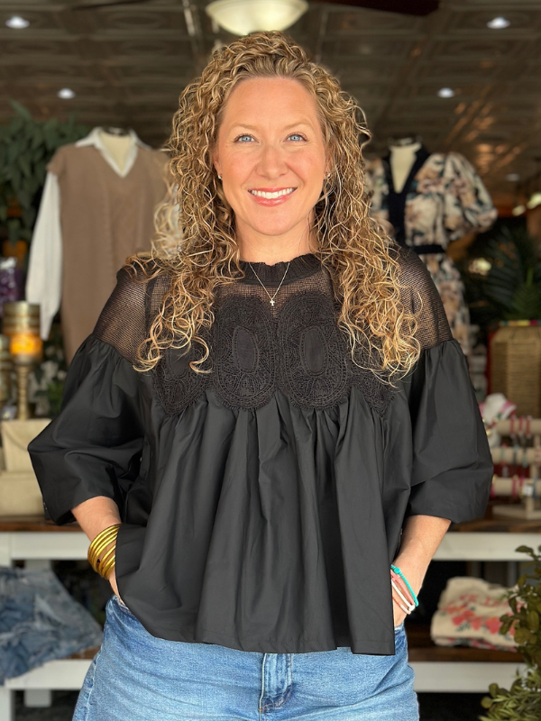 Woman wearing a black blouse with sheer details in a store setting