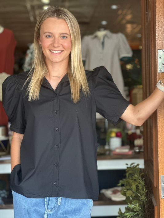Woman wearing a black blouse and blue jeans standing in a store.