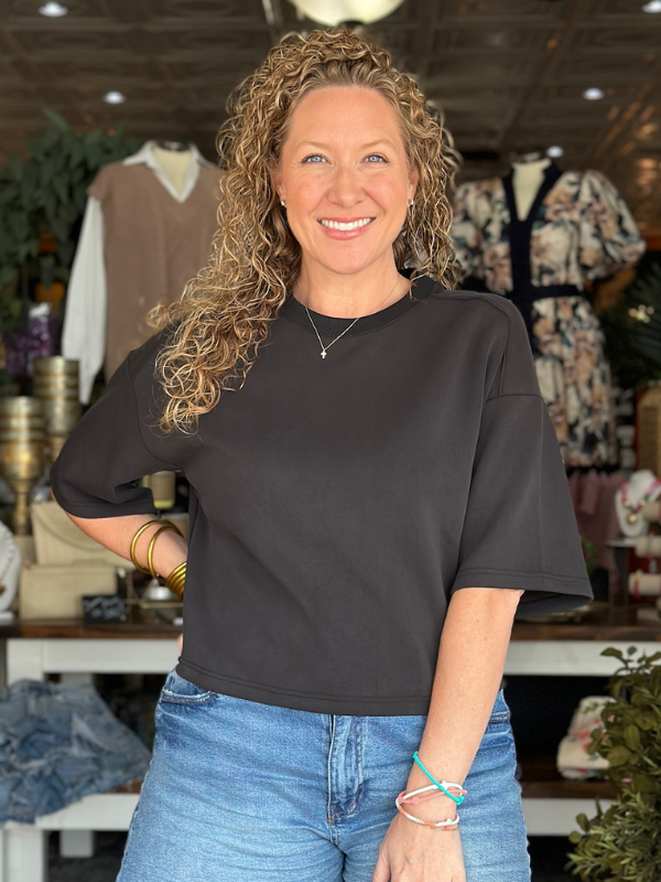 Woman wearing a black shirt and blue jeans standing in a clothing store.