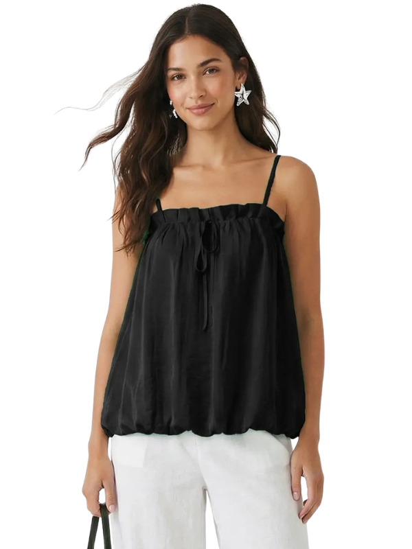 A woman wearing a black spaghetti-strap top with a gathered, ruffled neckline and a drawstring tie, paired with white pants, against a plain white background.
