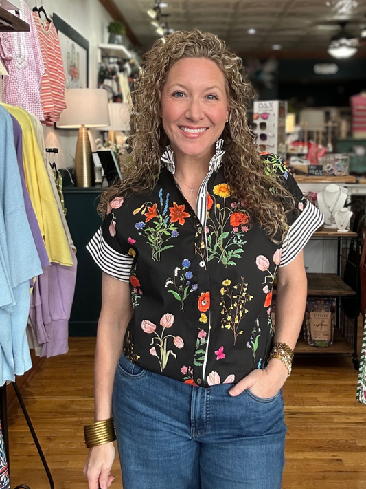 Woman wearing a floral embroidered vest in a clothing store.