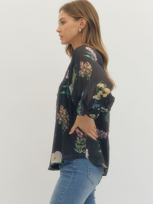 Woman wearing a dark floral patterned top and light blue jeans on a white background