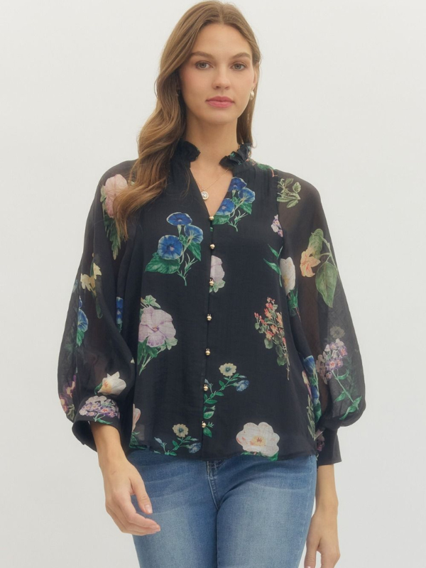 Woman wearing a black floral blouse with blue jeans on a white background
