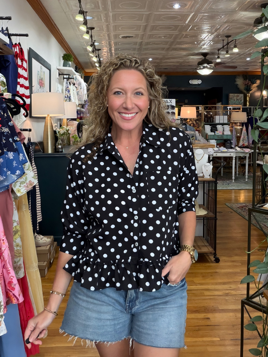 Woman wearing a black polka dot shirt and denim shorts in a store setting
